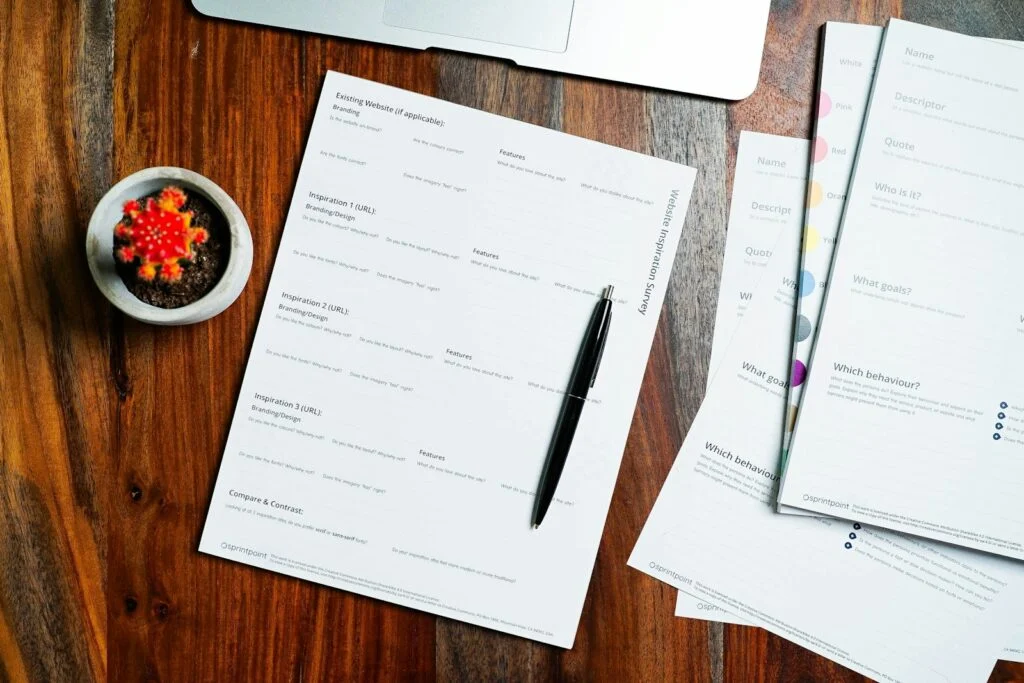 Wooden table topped with papers and a pen