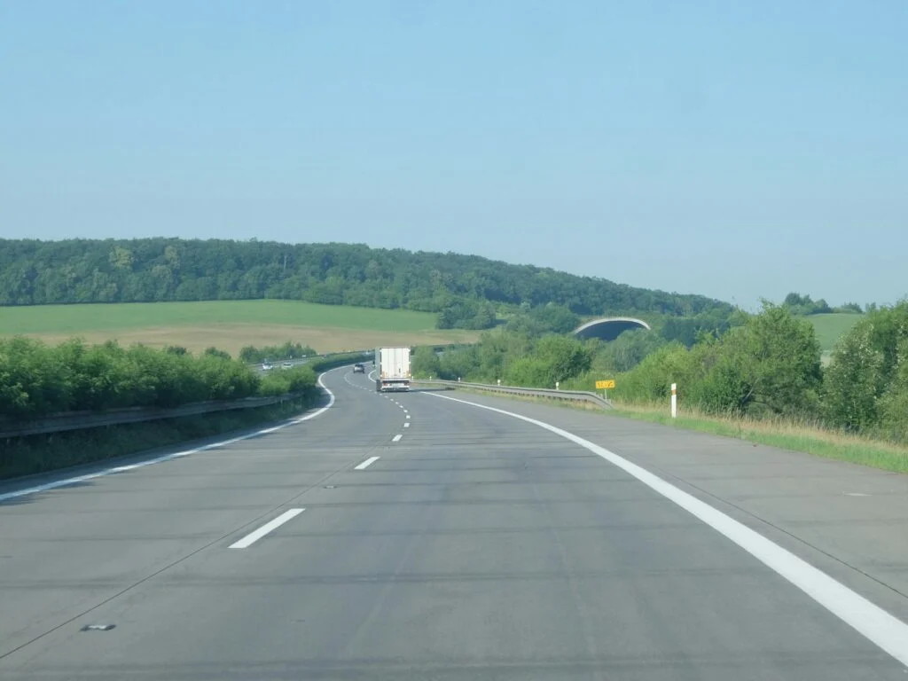 Truck on a highway through green hills under a clear sky